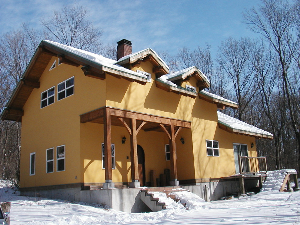 Cette image montre une façade de maison jaune chalet de taille moyenne et à un étage avec un toit à deux pans.