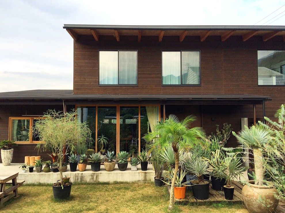 Réalisation d'une façade de maison marron asiatique en bois à un étage avec un toit à deux pans.