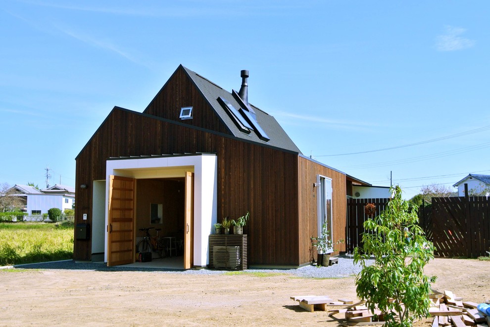 На фото: коричневый, деревянный дом в современном стиле с двускатной крышей