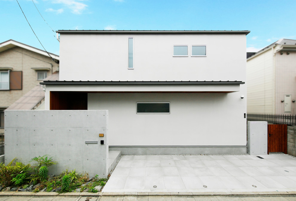 Mittelgroßes, Zweistöckiges Nordisches Einfamilienhaus mit Mix-Fassade, weißer Fassadenfarbe, Flachdach und Blechdach in Tokio
