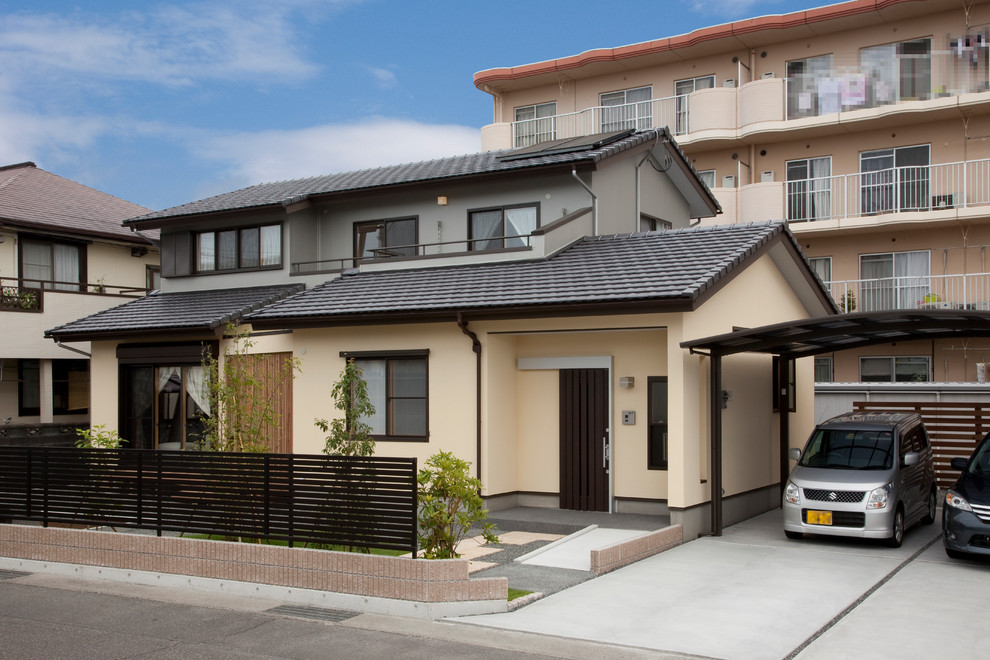Photo of a beige traditional house exterior in Kobe with a pitched roof.