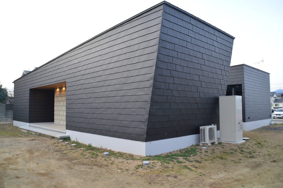 Réalisation d'une façade de maison métallique et noire minimaliste de plain-pied avec un toit en appentis.