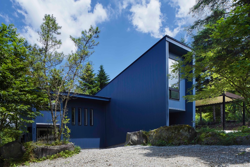 Aménagement d'une façade de maison bleue contemporaine de taille moyenne et à niveaux décalés avec un toit en appentis.