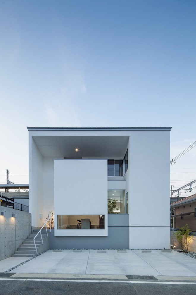 This is an example of a medium sized and white modern split-level house exterior in Other with a flat roof.