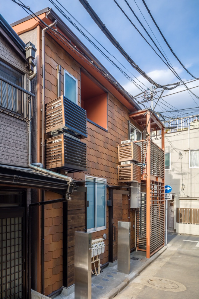 東京23区にある低価格の中くらいな北欧スタイルのおしゃれな家の外観 (塗装レンガ、オレンジの外壁) の写真