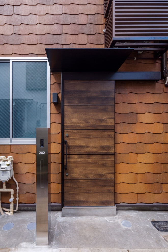 Mittelgroßes, Zweistöckiges Skandinavisches Einfamilienhaus mit gestrichenen Ziegeln, oranger Fassadenfarbe, Satteldach und Schindeldach in Tokio