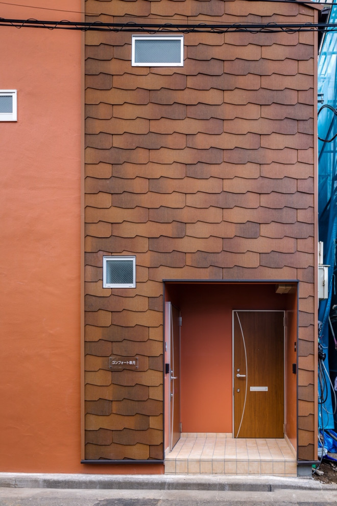 Стильный дизайн: двухэтажный, оранжевый частный загородный дом среднего размера в скандинавском стиле с облицовкой из крашеного кирпича, двускатной крышей и крышей из гибкой черепицы - последний тренд