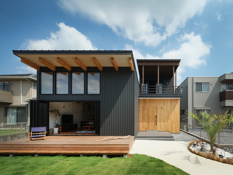 Cette photo montre une façade de maison métallique et noire bord de mer à un étage avec un toit en appentis et un toit en métal.