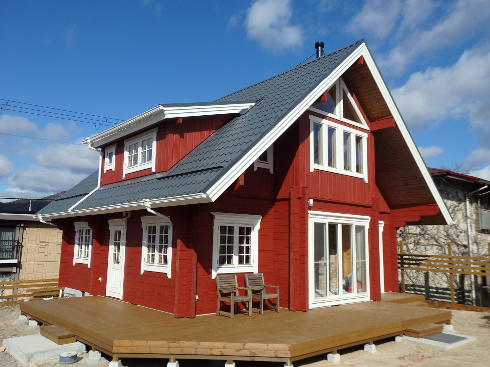 Exempel på ett mellanstort skandinaviskt rött hus, med två våningar, sadeltak och tak i metall