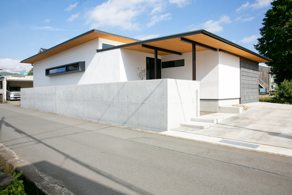 Immagine della facciata di una casa bianca contemporanea a un piano di medie dimensioni con rivestimento in stucco e copertura in metallo o lamiera