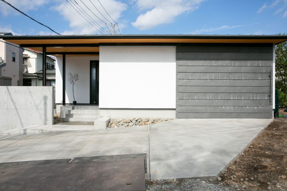 Cette image montre une façade de maison blanche design en stuc de taille moyenne et de plain-pied avec un toit en appentis et un toit en métal.