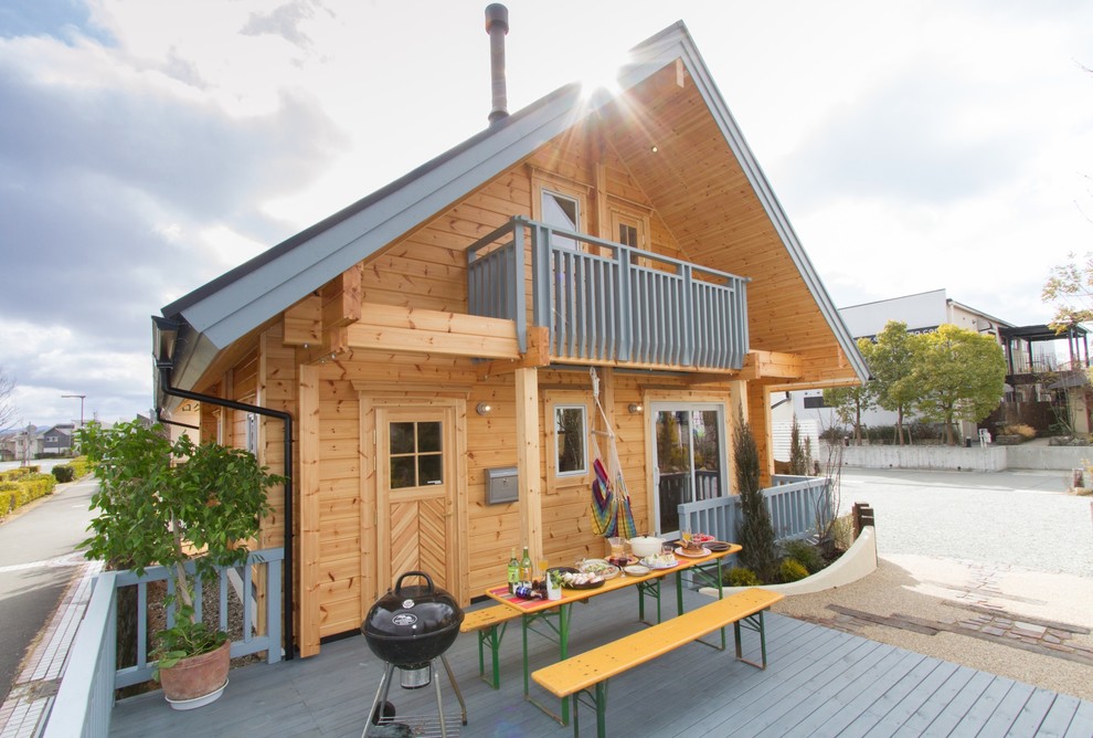 На фото: деревянный, коричневый дом из бревен в скандинавском стиле с двускатной крышей