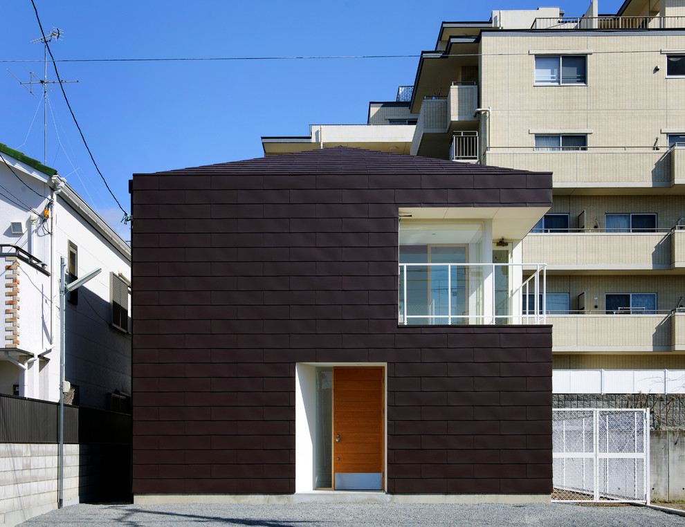 Idée de décoration pour une façade de maison noire minimaliste en bois à un étage avec un toit à quatre pans.