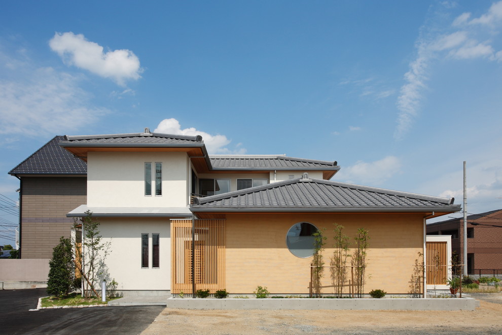 Aménagement d'une façade de maison multicolore asiatique avec un toit à quatre pans et un toit en tuile.