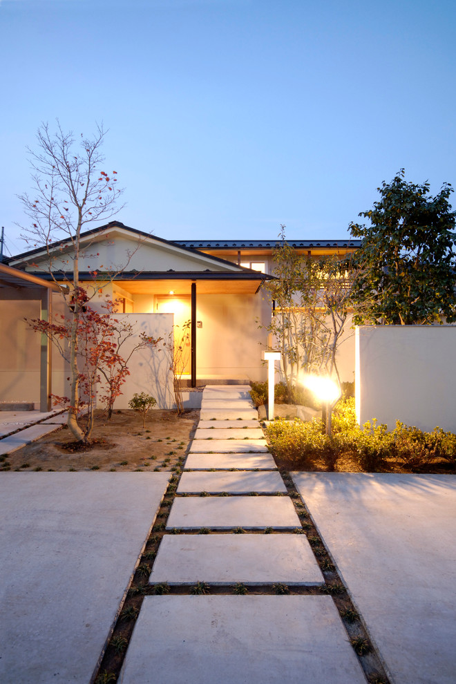 Réalisation d'une façade de maison blanche asiatique à un étage avec un toit à croupette.