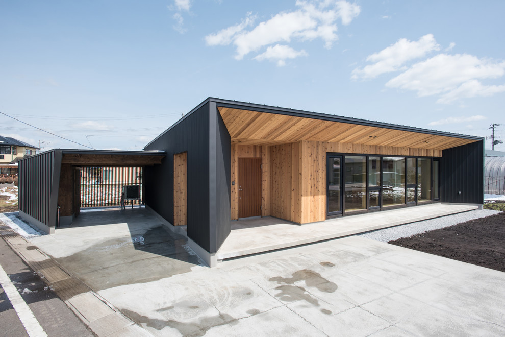 Ejemplo de fachada de casa negra moderna pequeña de una planta con revestimiento de madera, tejado de un solo tendido y tejado de metal