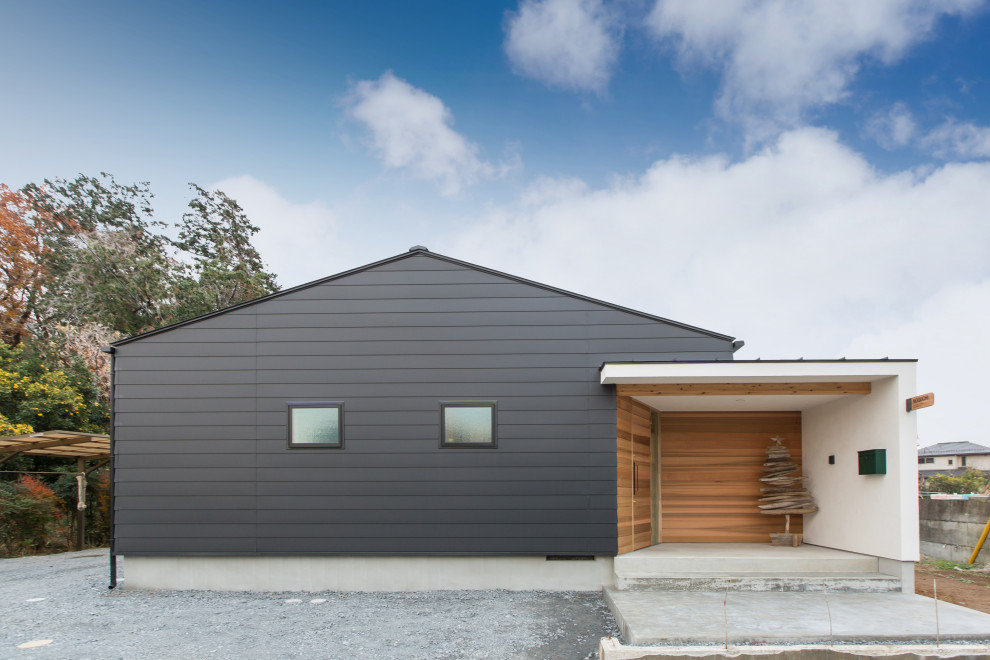 Diseño de fachada de casa negra industrial pequeña de una planta con revestimiento de metal, tejado a dos aguas y tejado de metal