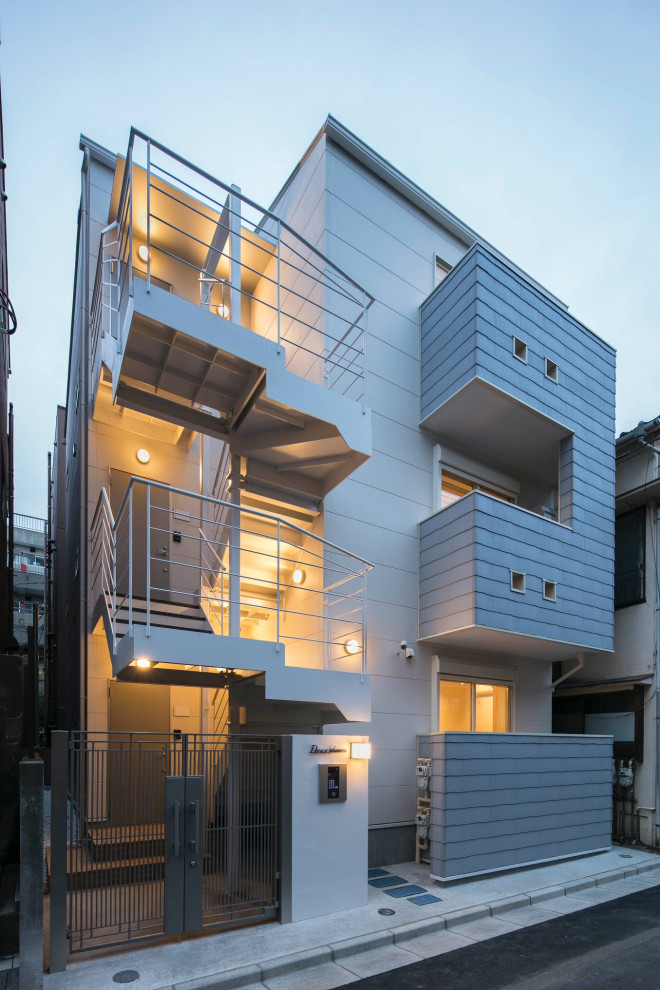 Kleines, Dreistöckiges Nordisches Einfamilienhaus mit Faserzement-Fassade, weißer Fassadenfarbe, Satteldach und Blechdach in Tokio