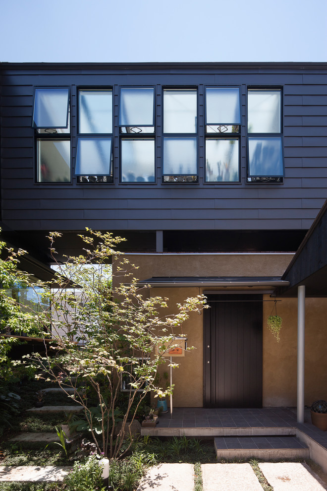 Zweistöckiges Modernes Haus mit schwarzer Fassadenfarbe, Flachdach und Blechdach in Yokohama