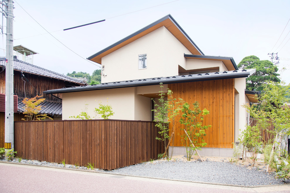 Inspiration pour une façade de maison beige asiatique de taille moyenne et à un étage avec un toit en appentis et un toit en métal.