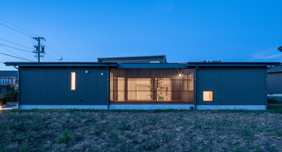 На фото: одноэтажный, зеленый частный загородный дом среднего размера в скандинавском стиле с односкатной крышей, металлической крышей, облицовкой из металла, серой крышей и отделкой доской с нащельником
