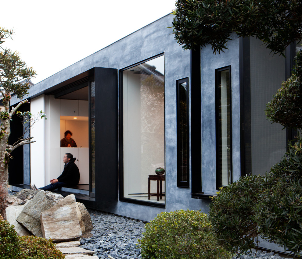 Diseño de fachada gris asiática de una planta con revestimientos combinados y tejado plano