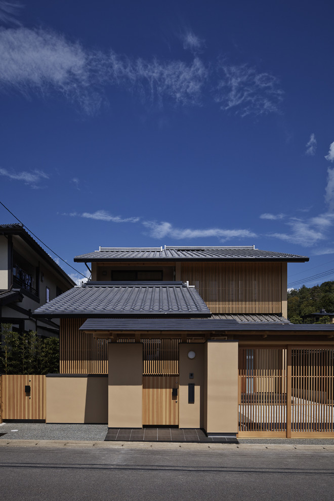 Свежая идея для дизайна: двухэтажный, бежевый дом в восточном стиле с двускатной крышей - отличное фото интерьера