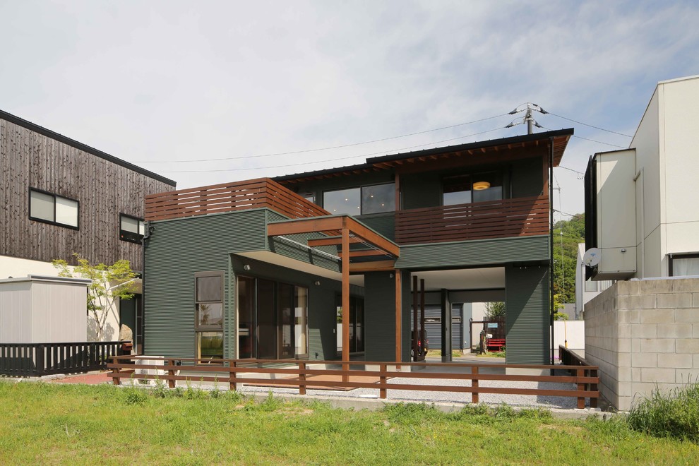 Esempio della casa con tetto a falda unica verde contemporaneo a due piani di medie dimensioni con copertura in metallo o lamiera