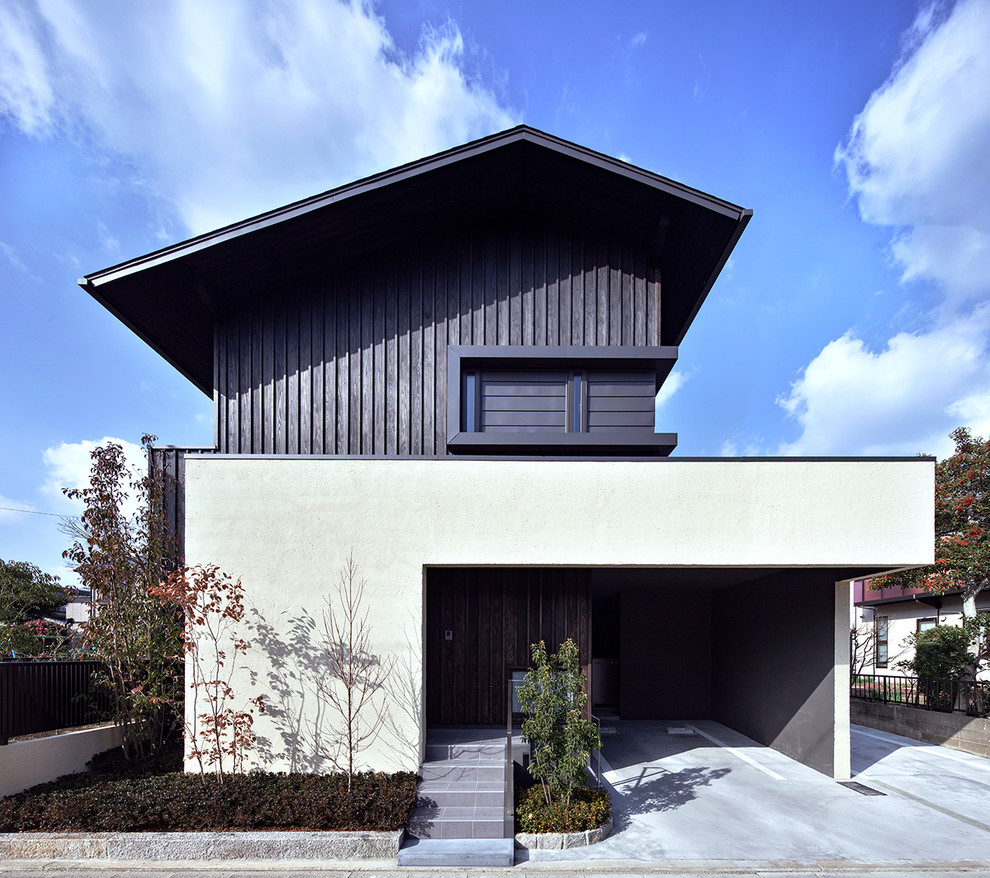 Aménagement d'une façade de maison blanche asiatique en bois de taille moyenne et à un étage avec un toit à deux pans et un toit en métal.