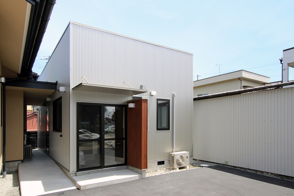 Cette photo montre une petite façade de maison métallique et grise moderne de plain-pied avec un toit en appentis et un toit en métal.