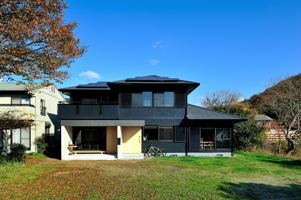 Cette photo montre une façade de maison noire asiatique à un étage avec un toit à quatre pans et un revêtement mixte.
