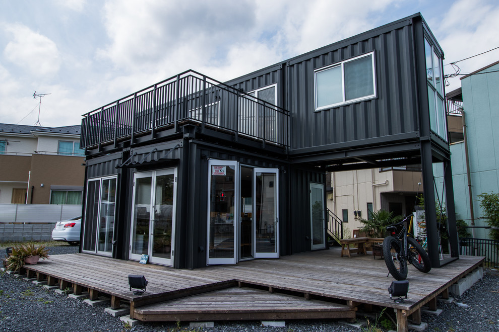 Cette photo montre une façade de maison container noire industrielle avec un toit plat.