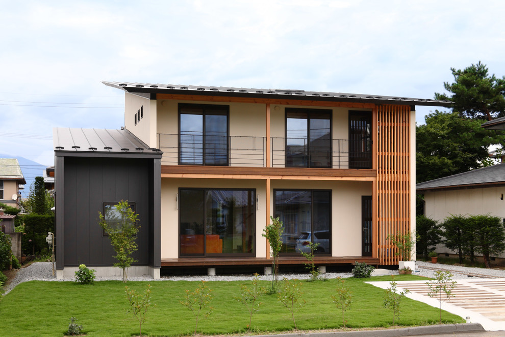 Réalisation d'une façade de maison beige asiatique en stuc à un étage avec un toit en appentis et un toit en métal.