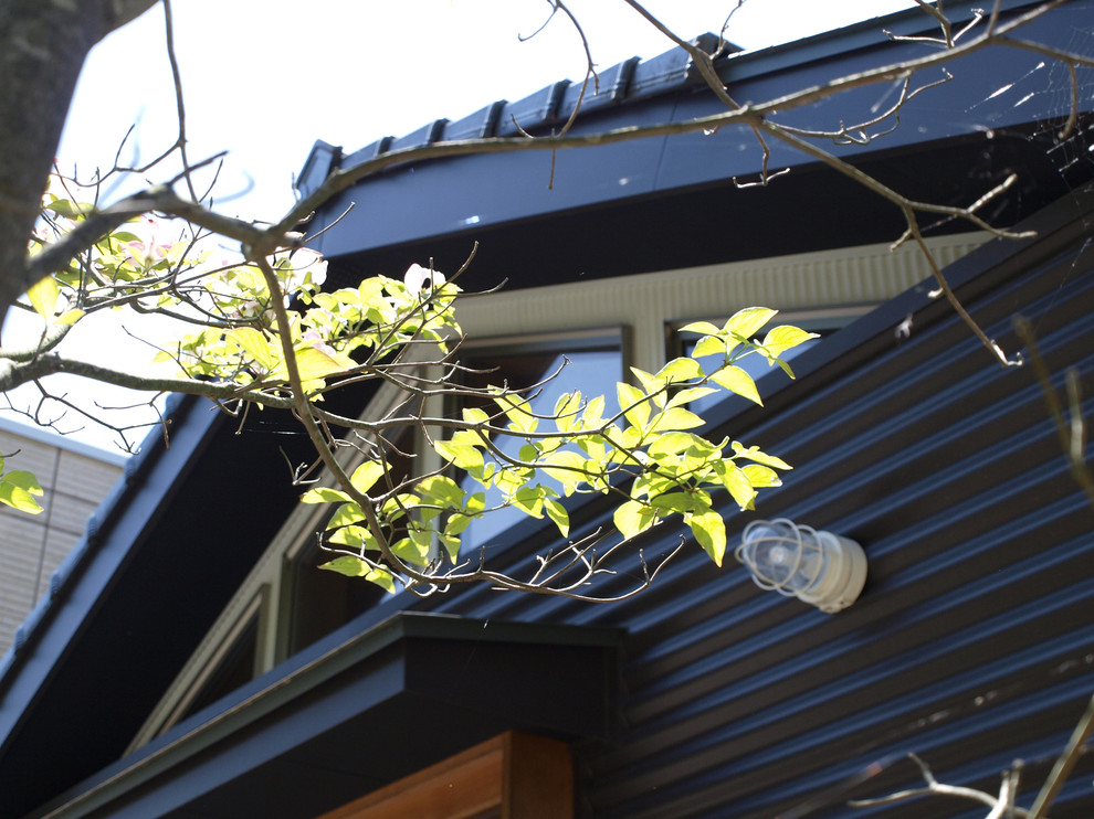 Cette photo montre une façade de maison métallique et marron moderne à un étage avec un toit à deux pans et un toit mixte.