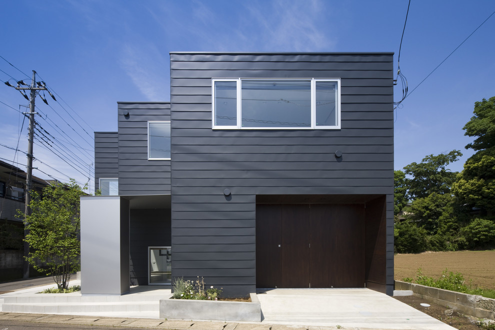 Exemple d'une façade de maison métallique et noire moderne de taille moyenne et à un étage avec un toit plat et un toit en métal.
