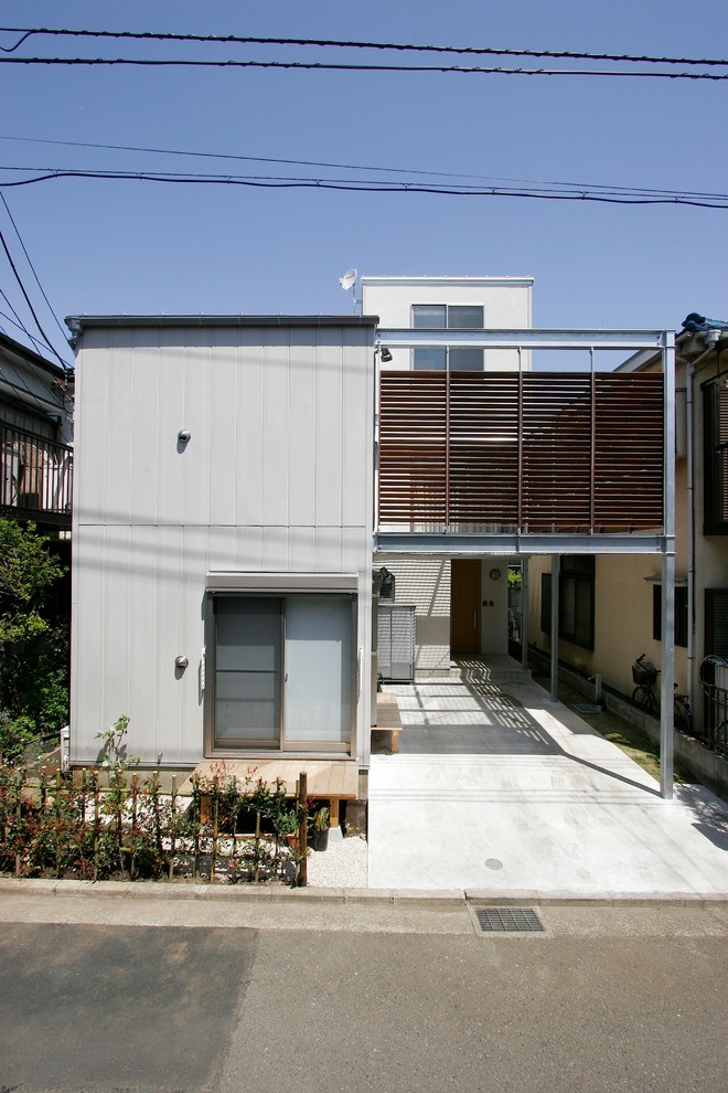 Cette photo montre une façade de maison grise moderne en panneau de béton fibré à deux étages et plus avec un toit à deux pans et un toit en métal.