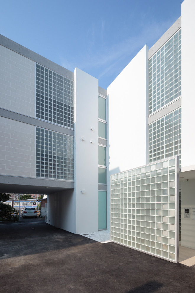 На фото: трехэтажный, белый многоквартирный дом в современном стиле с облицовкой из бетона и плоской крышей с