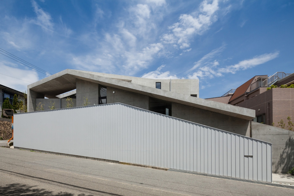 Imagen de fachada de casa gris urbana grande a niveles con revestimiento de hormigón y tejado de un solo tendido