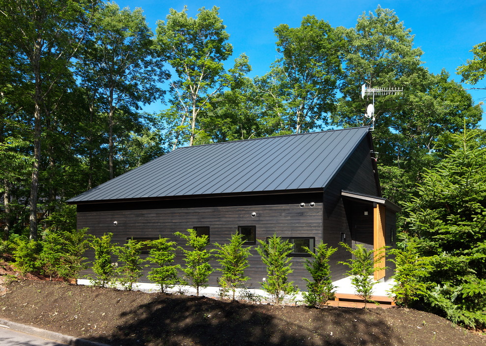 Foto della facciata di una casa nera country a un piano con tetto a capanna e rivestimento in legno