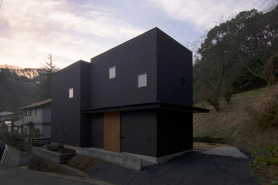 This is an example of a medium sized and black modern two floor house exterior in Other with a flat roof.