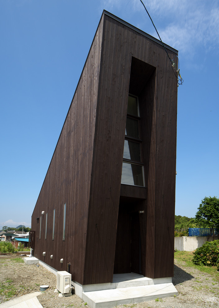 Bild på ett litet funkis brunt hus, med pulpettak, allt i ett plan och tak i metall