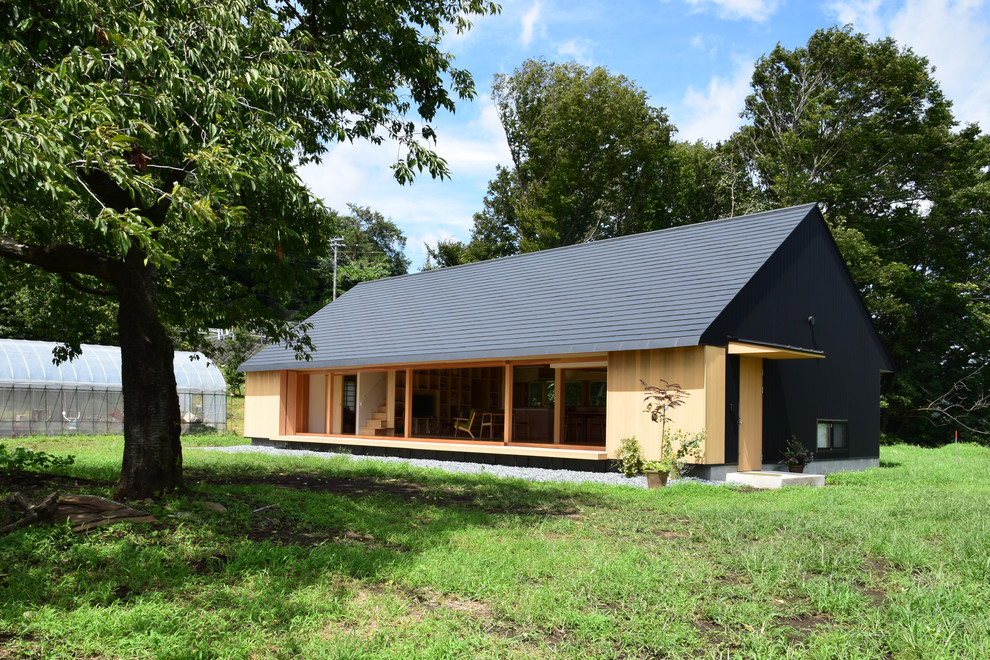 Diseño de fachada de casa negra de estilo zen de tamaño medio de una planta con tejado a dos aguas, revestimiento de metal y tejado de metal