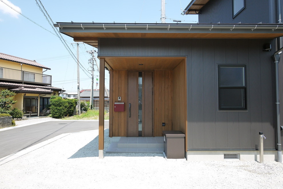 Réalisation d'une façade de maison métallique et noire asiatique à un étage avec un toit en métal et un toit à deux pans.
