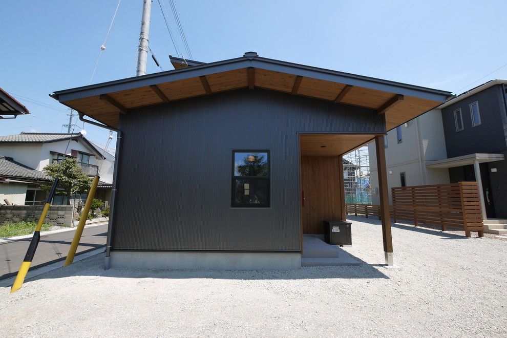 Idée de décoration pour une façade de maison métallique et noire asiatique à un étage avec un toit à deux pans et un toit en métal.