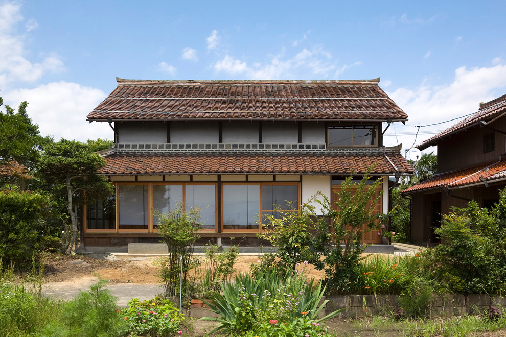 Réalisation d'une façade de maison blanche asiatique à un étage avec un toit à deux pans et un toit en tuile.