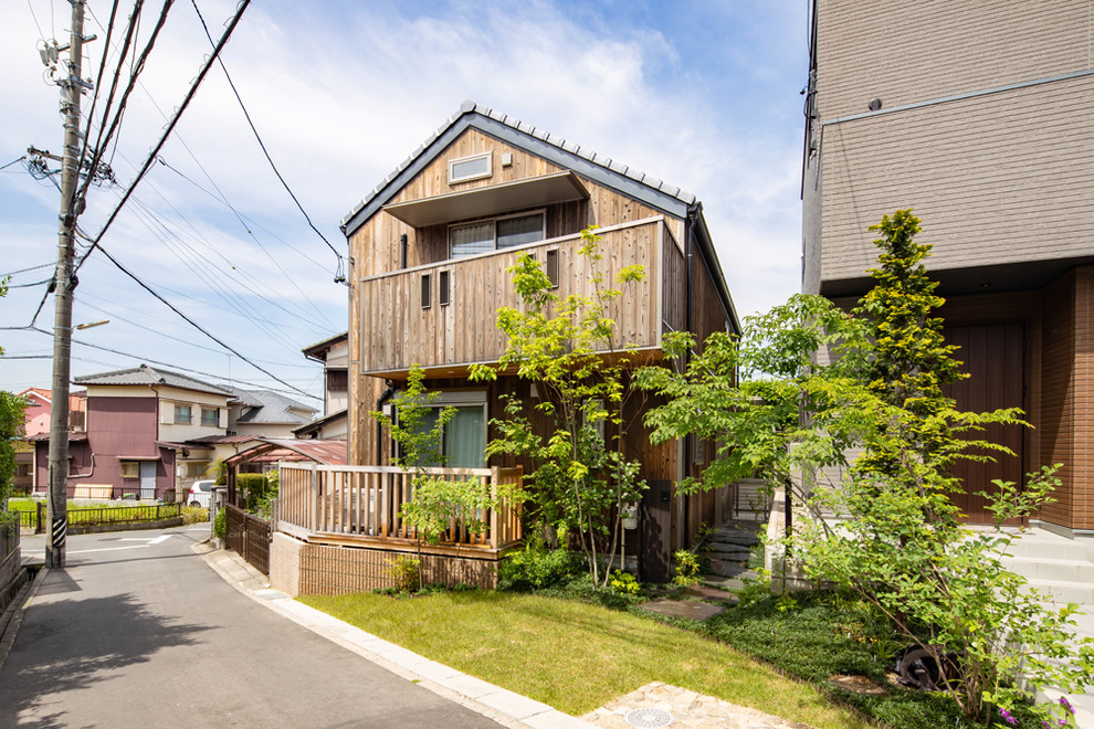 Diseño de fachada de casa marrón de estilo zen de dos plantas con revestimiento de madera y tejado a dos aguas