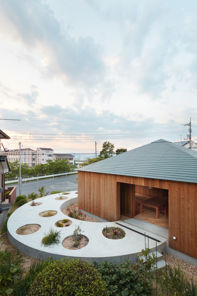 Diseño de fachada marrón de estilo zen de una planta con revestimiento de madera y tejado a cuatro aguas