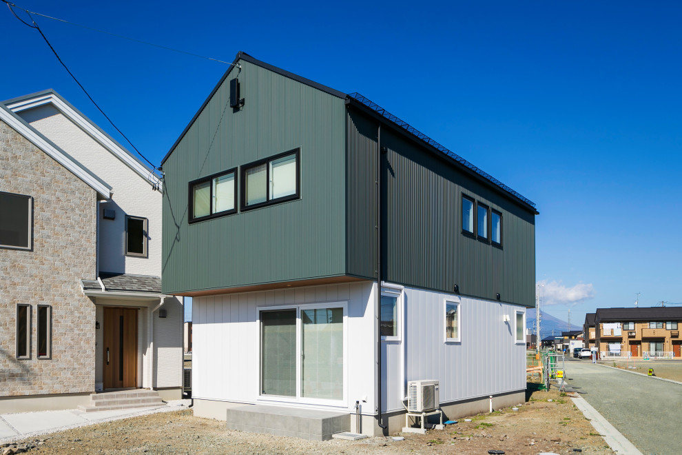 Cette image montre une façade de maison nordique en planches et couvre-joints de taille moyenne et à un étage avec un toit à deux pans, un toit en métal et un toit noir.
