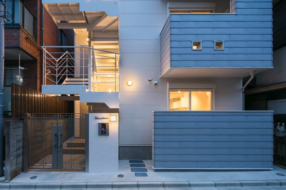 Mittelgroßes, Dreistöckiges Nordisches Einfamilienhaus mit gestrichenen Ziegeln, grauer Fassadenfarbe, Satteldach und Blechdach in Tokio
