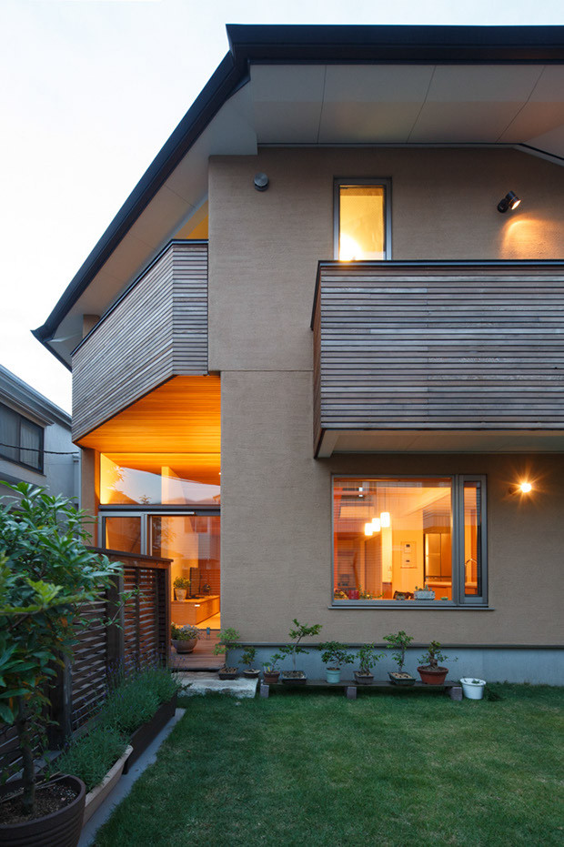 Diseño de fachada de casa marrón moderna de tamaño medio de tres plantas con revestimiento de estuco, tejado a cuatro aguas y tejado de metal